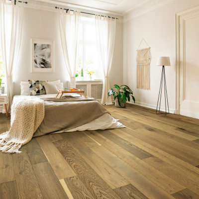 Natural oak hardwood flooring in a cozy Ann Arbor bedroom with soft neutral decor, and tall windows with white sheer curtains
